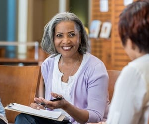 Woman talks with counselor holding a pen and clipboard.