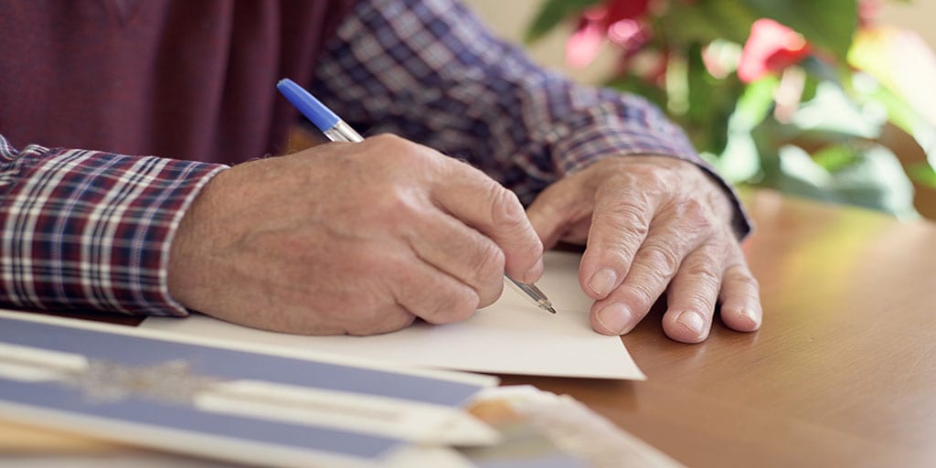 Elderly man contemplates what to write to someone in hospice